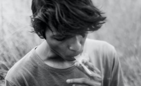 Młody człowiek pali papierosa w polu, szkodliwość dla płuc