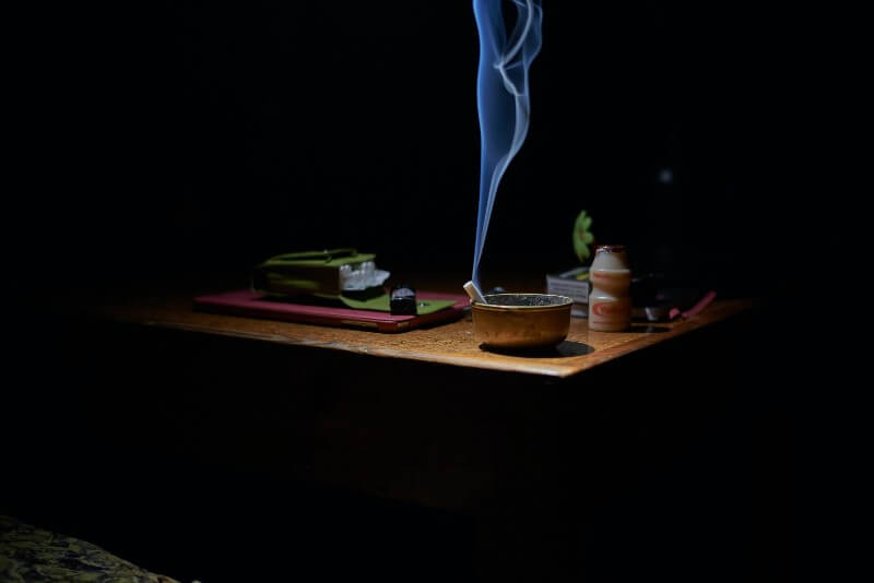 papieros w metalowej popielniczce pali się na stole w ciemnym pokoju